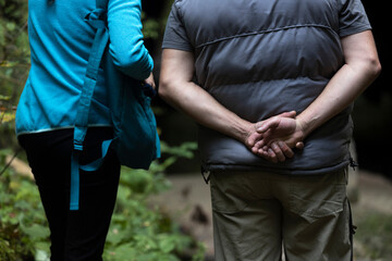 Couple Talking Outdoors in Nature With Man Holding Hands on his back While Listening to the Woman