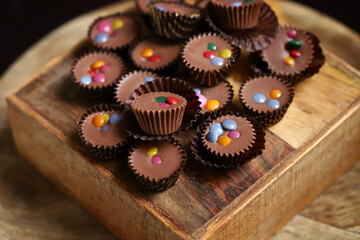 Selective focus. Macro. Small chocolate candies on a wooden board.