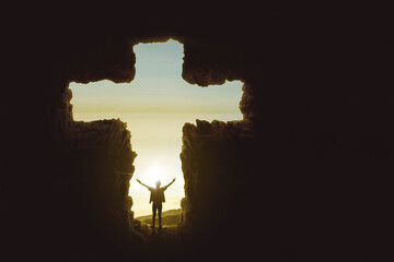 Man raising hands inside a cave shaped cross symbol
