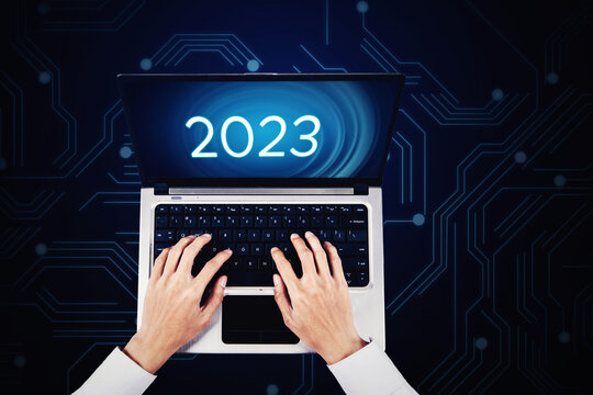 Man hands typing 2023 number on laptop monitor