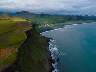 Fototapeta premium Beautiful aerial view of the town of Vik near the black sand beach and the basalt rock formations in Iceland