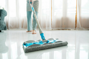 Young woman cleaning floor using mop at home.