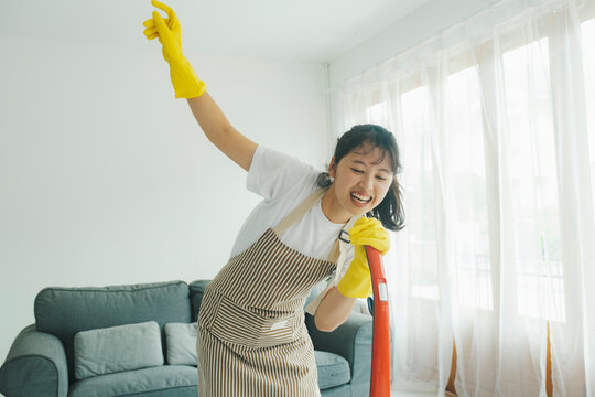 Young woman having fun while cleaning home.