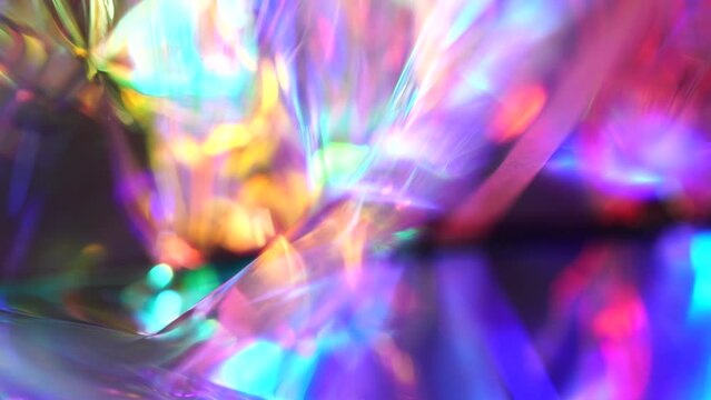 Holographic rainbow pink purple blue abstract moving festive background. Glow and glare. Lights and rays through a glass crystal