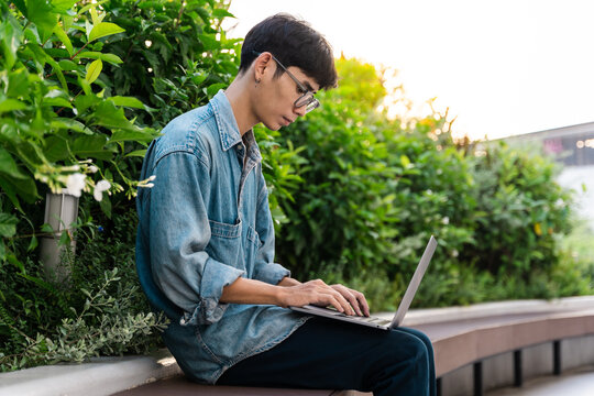 image of asian boy sitting and using computer in school campus