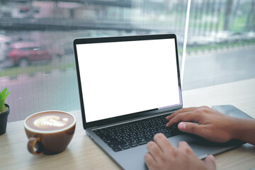 Mockup image of a businesswoman using laptop with blank white desktop screen with coffee cup on wooden table in cafe.