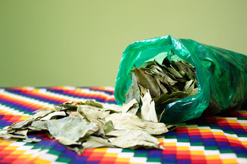 Coca leaves on table, Aymara and Inca indigenous cloth. Traditional use of coca in the Andean zone,...
