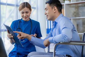 Asian female doctors encourage and support male patients in wheelchairs after consulting and health check in the concept of hospital, clinic