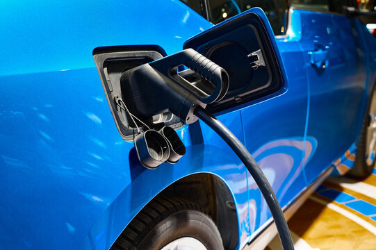 Charging electric blue automobile with plug at power station