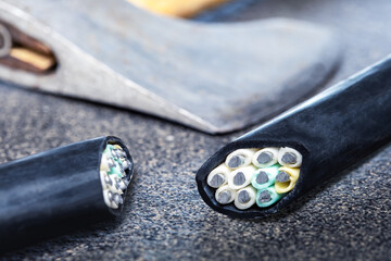 Sabotage concept. cutting electrical cable and axe on dark surface.