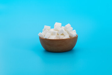 Sugar cubes in a bowl on blue background