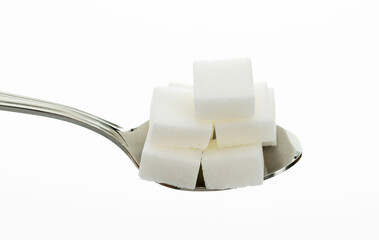 Sugar cubes in a spoon on white background