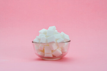 Sugar cubes in a bowl on pink background