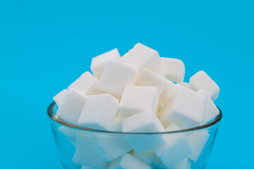 Sugar cubes in a bowl on blue background
