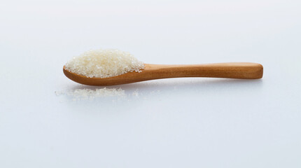 Wooden spoon with sugar crystals on white background