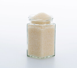 Granulated sugar in glass jar on white background