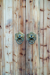 ancient wooden gate with two door knocker rings close-up