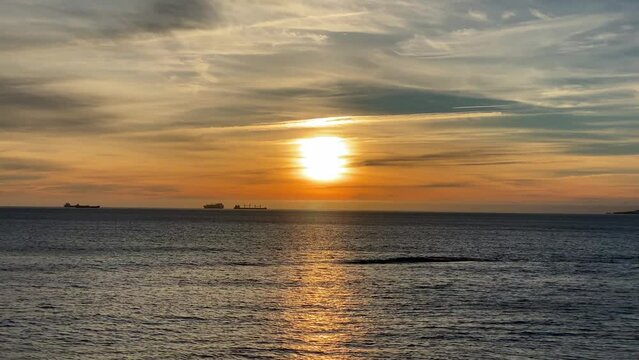 4k Big Sunset Over Ocean with some boats sailing. Clouds creating amazing atmosphere.