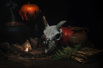 Magic altar. Goats skull, witches hand with sharp black nails holds a small pumpkin, burning candle...