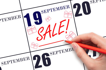 Hand writing text SALE and drawing gift boxes on calendar date September 19. Shopping Reminder