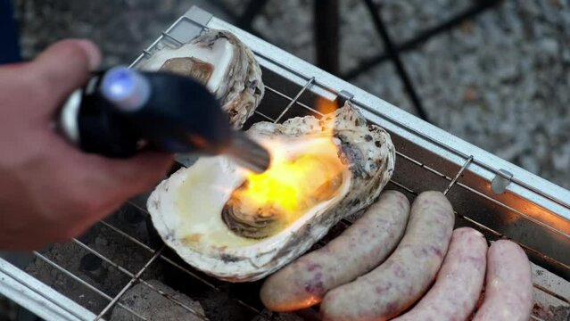 Close up Belcheri oyster beside sausage on steel grill is cooked by flame fire of gas burner