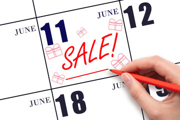 Hand writing text SALE and drawing gift boxes on calendar date June 11. Shopping Reminder