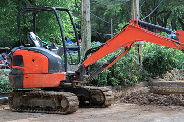 The orange mini Backhoe or Crawler excavator (Tracked excavator) is parked at the construction site