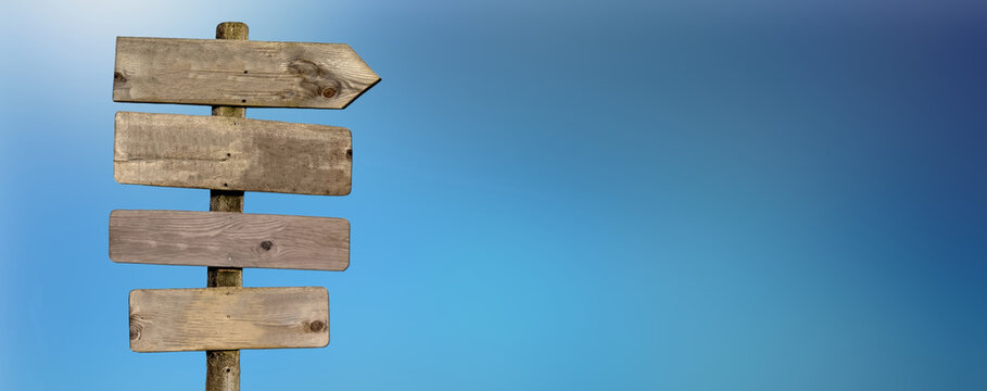 wooden directional post with arrow pointing right on blue sky background