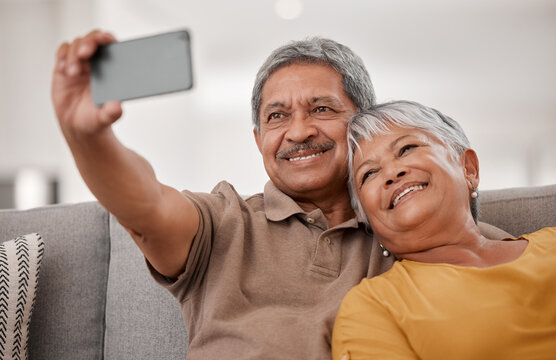 Phone, selfie and love with a senior couple taking a photograph while sitting on the living room sofa of a home together. Mobile, happy and smile with an elderly male and female psong for a picture