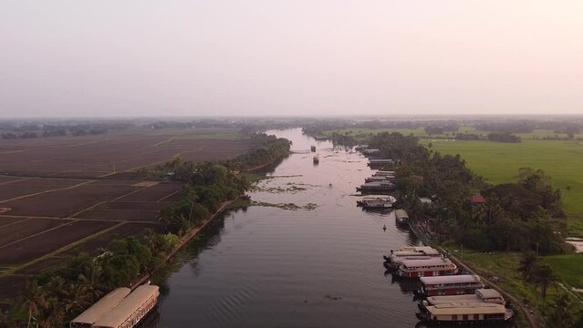 Aerial slow movement around port with boats surrounded by dense trees in Kerela