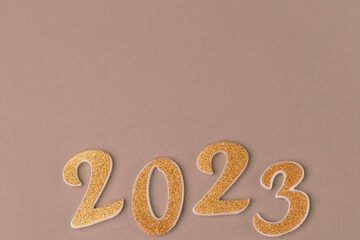 Numbers 2023 in golden color on a beige background. Upcoming new year, copy space