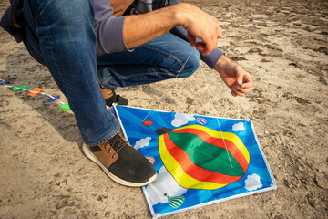 a man ties a rope on a children's kite. tying a kite. preparing for the flight