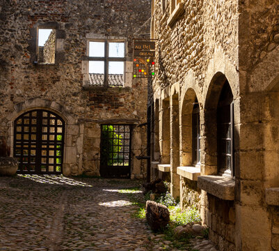 Old medieval street with stone houses, between light and shadow, in the famous village P&eacute;rouges, Ain.