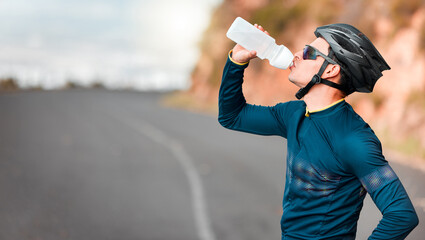 Road, fitness and cycling man drinking water by a mountain tired from workout, cardio exercise and training. Bicycle, sports and thirsty biker refreshing with a healthy beverage or liquid in Texas