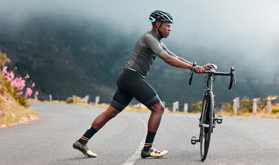 Stretching legs, fitness and man cycling on a road with a bike in the mountains for cardio, travel and sports workout in nature. Athlete doing a warm up before training on a bicycle in the street