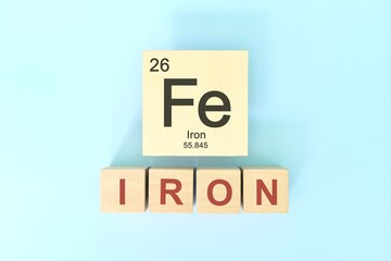 Iron chemical element symbol with atomic mass and atomic number in wooden blocks flat lay composition. Chemistry and Science concept.