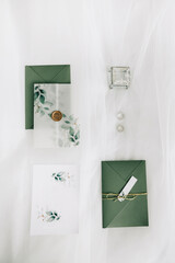 Wedding set of invitation printing with tracing paper in delicate white-green colors with wax seal. Invitation, envelope, rings and box.