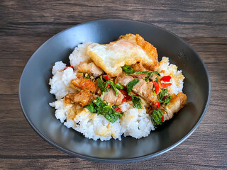 Rice topped with stir-fried pork and basil with a fried egg on the table