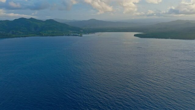 Aerial forward over calm and blue waters of Maimon Bay at sunset, Puerto Plata in Dominican Republic