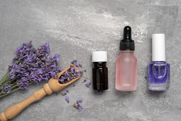 Flat lay composition with lavender flowers and natural essential oil on gray background. Botanical cosmetics
