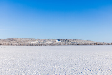 Fototapeta na wymiar Snowy fields with a hill on a sunny winter day