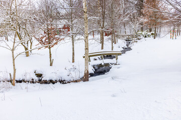 Stream in a garden with footbridge a snowy winter day