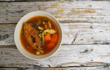 Tamarind curry with fried fish and vegetables on wooden floor - Thai style  That is delicious and has been very popular.
