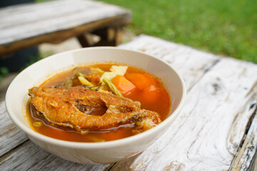Tamarind curry with fried fish and vegetables on wooden floor - Thai style  That is delicious and has been very popular.