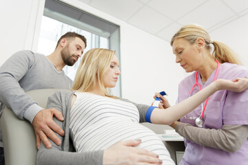 gynaecologist tightening tourniquet on pregnant woman to take blood sample