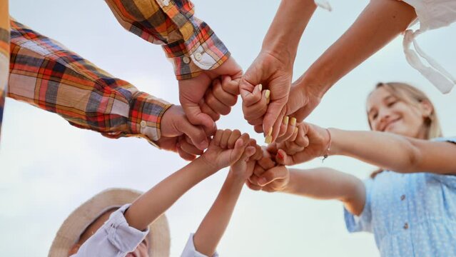 Parents and children stretched out their arms to center, stood in circle and clenched their fists. Unity and together. Relatives. Happiness and love in family. Team spirit. Top view of people hands.