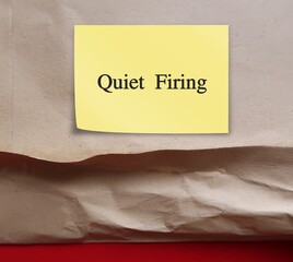 Torn office envelope with handwritten stick note Quiet Firing - refers to employers who treat workers badly to the point they will quit, instead of firing them