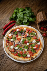 pizza with eggplant, cheese, tomatoes and chili peppers in a restaurant
