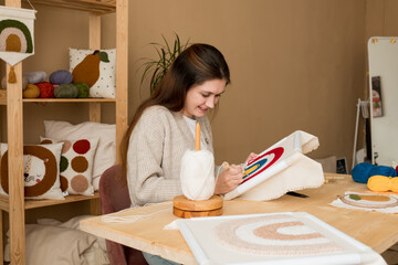 Young woman pushing the punchneedle straight down into the foundation fabric in workshop. Female...