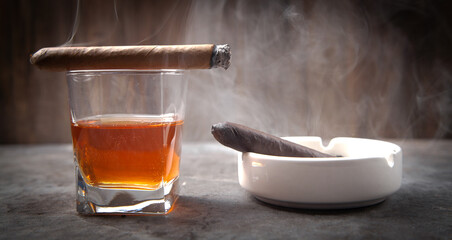 Glass of whisky, ashtray and cigar on the table.